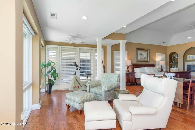 living room featuring vaulted ceiling, ceiling fan, light hardwood / wood-style floors, and decorative columns