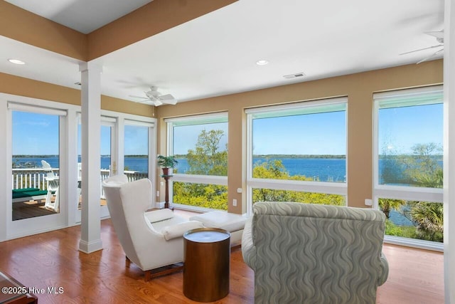 sunroom featuring a water view and ceiling fan