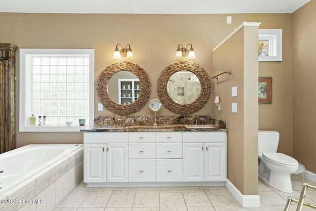 bathroom with toilet, vanity, tile patterned flooring, and a relaxing tiled tub