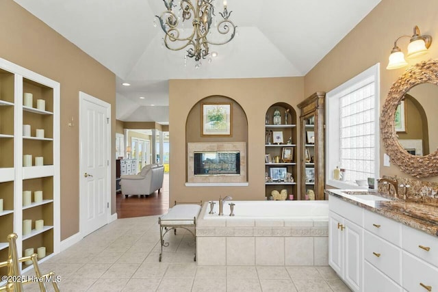 bathroom with built in shelves, vaulted ceiling, a notable chandelier, and tiled tub