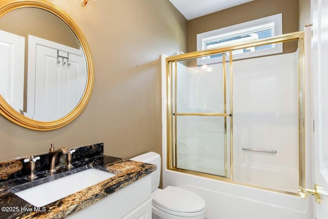 full bathroom with toilet, bath / shower combo with glass door, and vanity