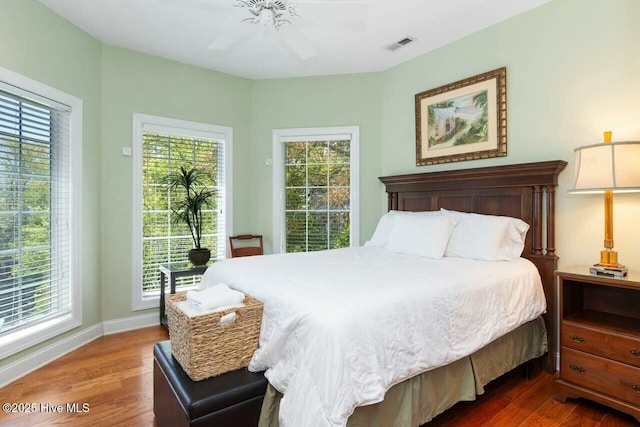 bedroom with ceiling fan, dark hardwood / wood-style flooring, and multiple windows