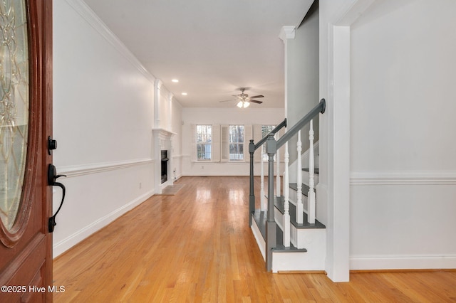 foyer featuring ornamental molding, light wood-type flooring, and ceiling fan