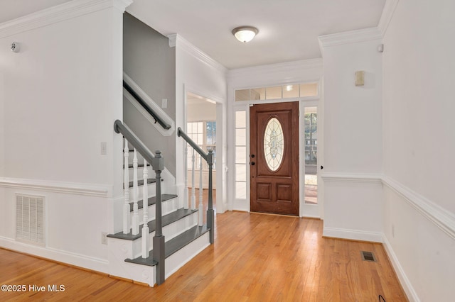 foyer entrance with ornamental molding and light wood-type flooring