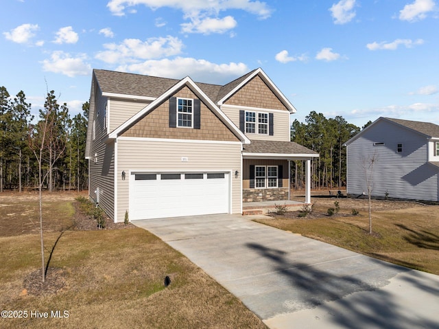 view of front of home featuring a garage, a front yard, and covered porch