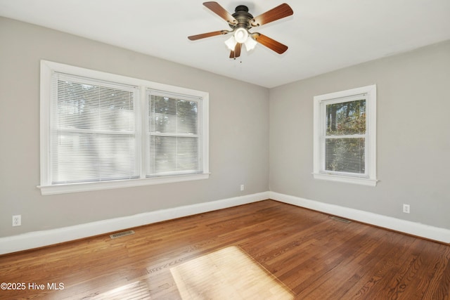 unfurnished room with ceiling fan, a wealth of natural light, and hardwood / wood-style flooring