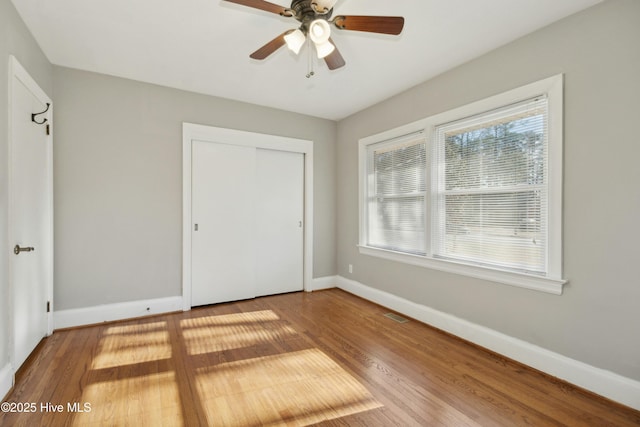 unfurnished bedroom featuring a closet, hardwood / wood-style floors, and ceiling fan