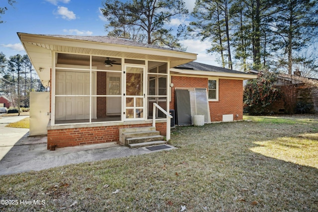 rear view of property featuring ceiling fan, a sunroom, and a yard