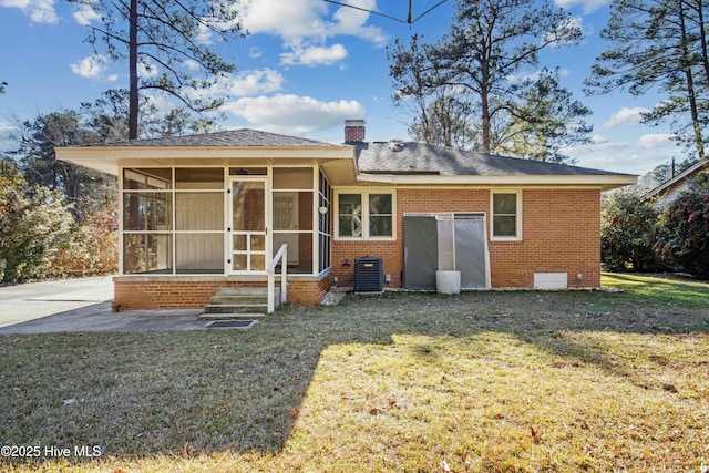 rear view of house with central air condition unit, a patio, a yard, and a sunroom