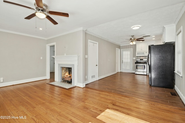 unfurnished living room featuring ceiling fan, crown molding, and light hardwood / wood-style flooring