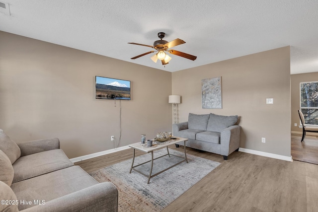 living room with ceiling fan, a textured ceiling, and hardwood / wood-style flooring