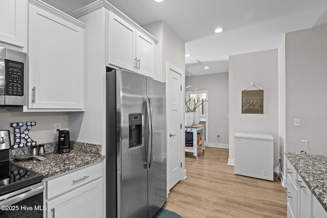 kitchen featuring white cabinets, stainless steel appliances, and dark stone counters