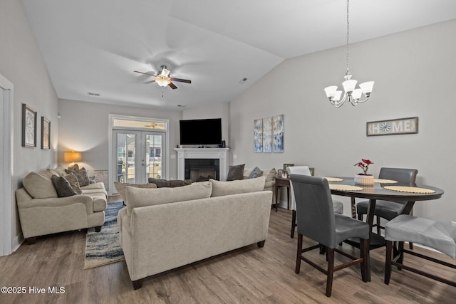 living room featuring wood-type flooring, ceiling fan with notable chandelier, lofted ceiling, and french doors