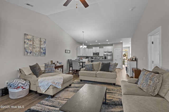 living room with hardwood / wood-style flooring, ceiling fan with notable chandelier, and lofted ceiling