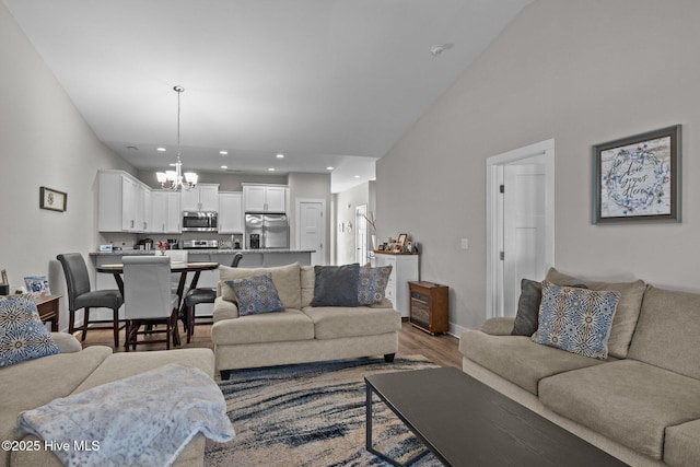 living room with a chandelier, hardwood / wood-style floors, and lofted ceiling