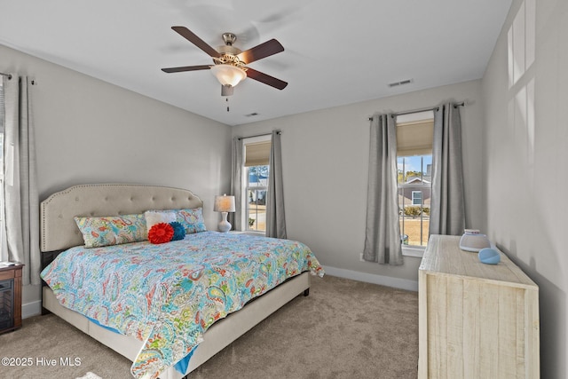 bedroom featuring ceiling fan, light colored carpet, and multiple windows