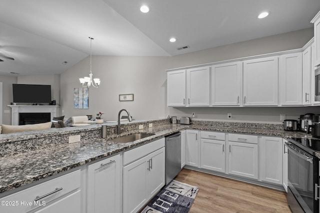 kitchen with vaulted ceiling, appliances with stainless steel finishes, sink, white cabinets, and light wood-type flooring