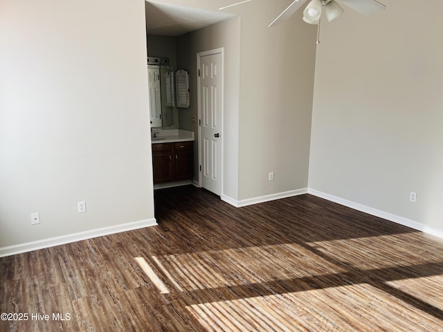 unfurnished bedroom featuring dark wood-type flooring, ceiling fan, connected bathroom, and sink