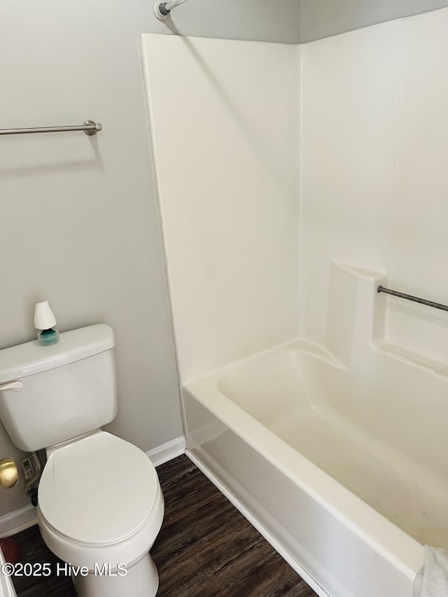 bathroom with wood-type flooring, shower / bathtub combination, and toilet