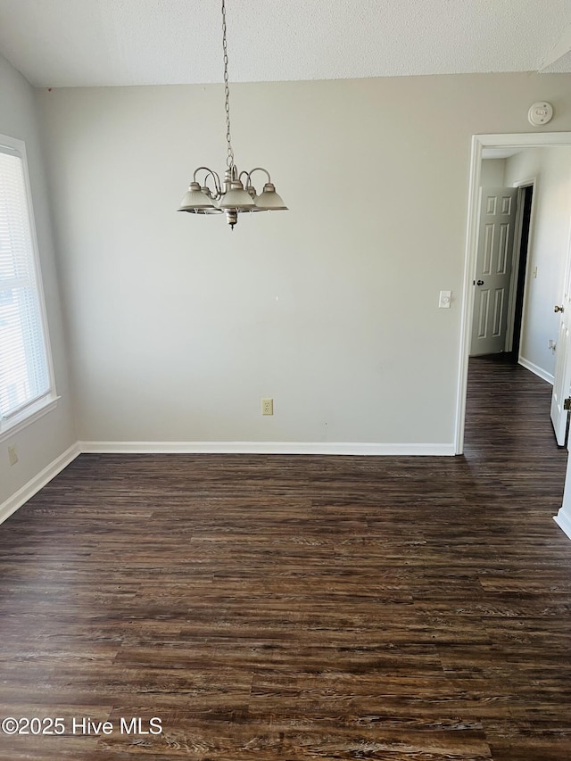 unfurnished room featuring dark hardwood / wood-style flooring, a chandelier, and a textured ceiling