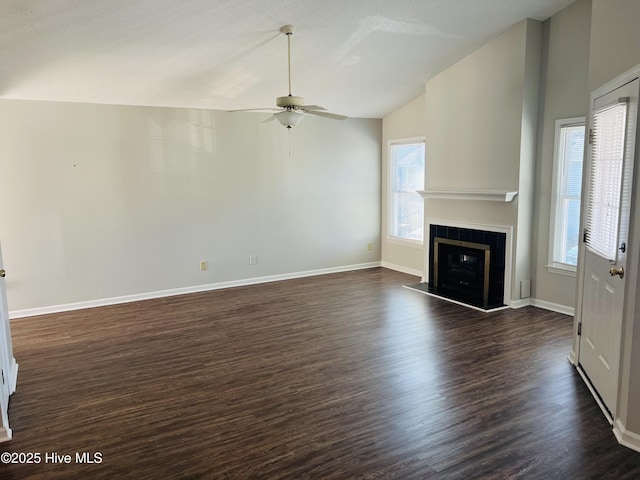 unfurnished living room featuring vaulted ceiling, dark hardwood / wood-style floors, and a healthy amount of sunlight