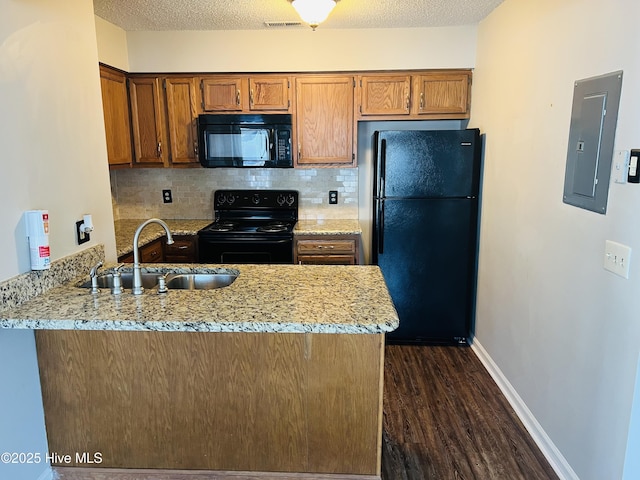 kitchen with sink, light stone counters, electric panel, kitchen peninsula, and black appliances