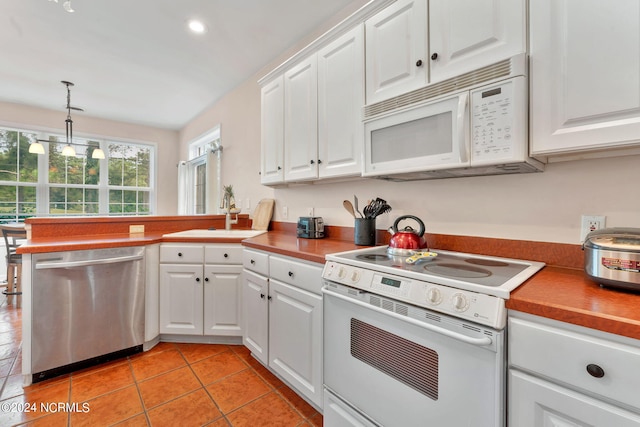 kitchen featuring decorative light fixtures, sink, light tile patterned floors, white appliances, and white cabinets