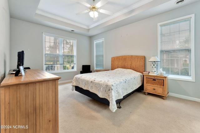 bedroom featuring ceiling fan, light colored carpet, multiple windows, and a tray ceiling