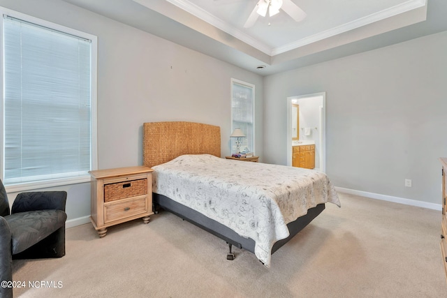 carpeted bedroom featuring ceiling fan, crown molding, a tray ceiling, multiple windows, and connected bathroom