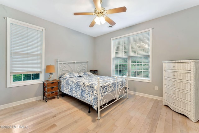 bedroom featuring ceiling fan, multiple windows, and light hardwood / wood-style flooring