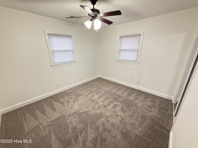 unfurnished room with ceiling fan and dark carpet