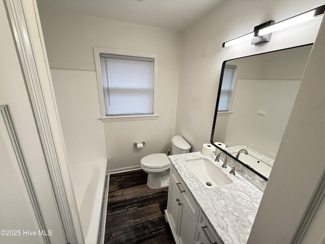 bathroom with toilet, vanity, wood-type flooring, and a washtub