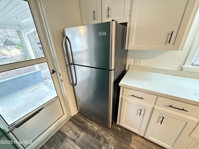 kitchen with stainless steel fridge, white cabinetry, and dark hardwood / wood-style floors