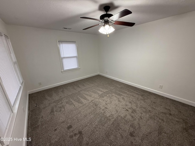 empty room featuring a textured ceiling, ceiling fan, and dark carpet