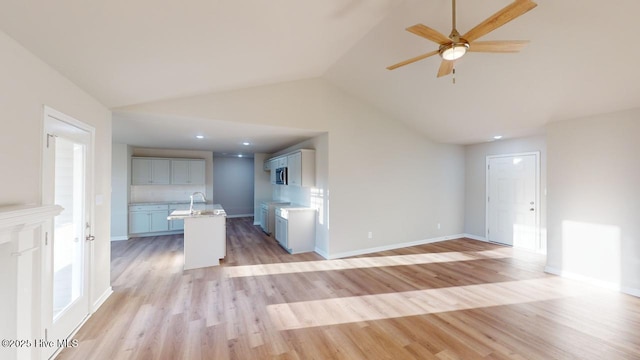 unfurnished living room featuring ceiling fan, lofted ceiling, light hardwood / wood-style floors, and sink