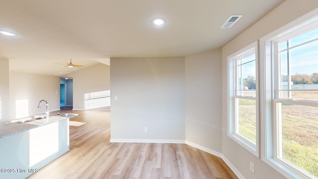 kitchen with ceiling fan, light hardwood / wood-style floors, plenty of natural light, and light stone counters