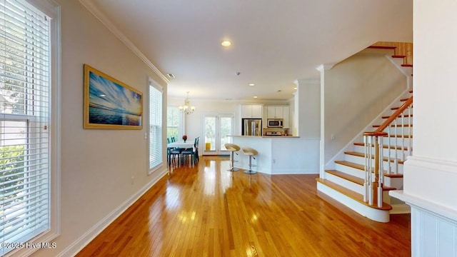 living room featuring crown molding, light hardwood / wood-style floors, and a notable chandelier