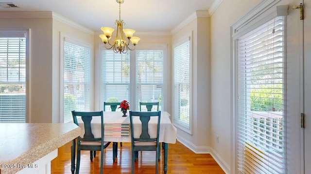 dining area featuring crown molding, a notable chandelier, and light wood-type flooring