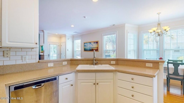 kitchen featuring white cabinets, dishwasher, an inviting chandelier, decorative backsplash, and sink