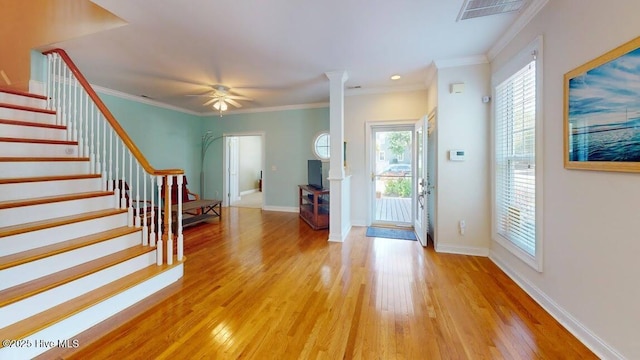 foyer entrance featuring a wealth of natural light, ornamental molding, and light wood-type flooring