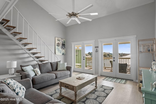 living room with ceiling fan, french doors, high vaulted ceiling, and light hardwood / wood-style floors