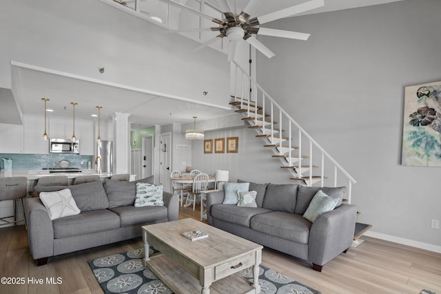 living room featuring light wood-type flooring, ceiling fan, and sink