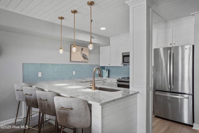 kitchen featuring light stone counters, white cabinets, appliances with stainless steel finishes, and kitchen peninsula