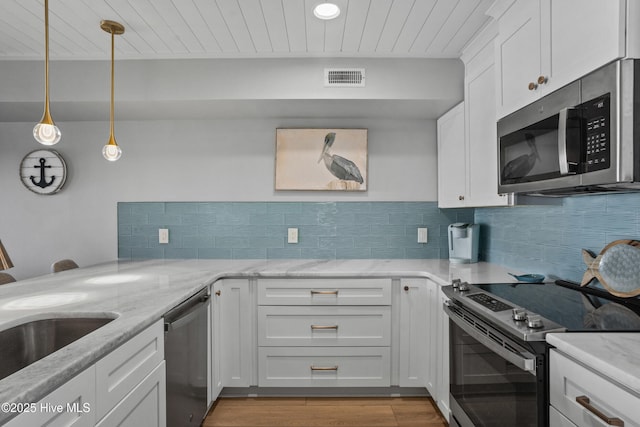 kitchen featuring hanging light fixtures, white cabinets, light stone countertops, and stainless steel appliances