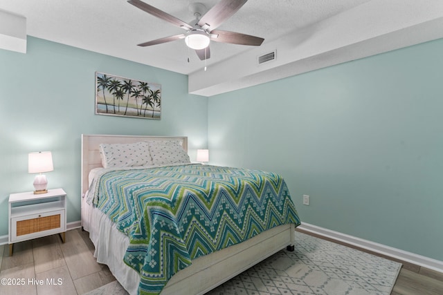 bedroom with ceiling fan, hardwood / wood-style floors, and a textured ceiling