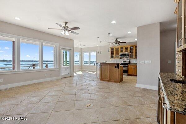 kitchen with appliances with stainless steel finishes, stone countertops, decorative light fixtures, a center island, and a water view