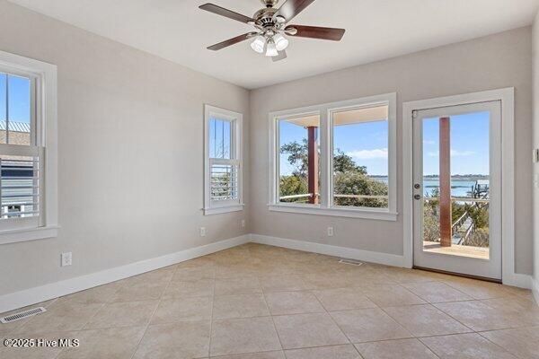 spare room featuring a water view, ceiling fan, and light tile patterned floors