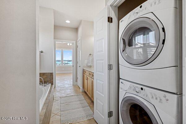 laundry room with stacked washer and clothes dryer and light tile patterned floors