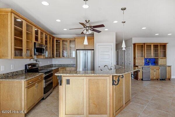 kitchen featuring pendant lighting, light tile patterned floors, stainless steel appliances, light stone counters, and an island with sink