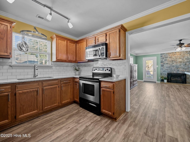 kitchen with light stone counters, ornamental molding, stainless steel appliances, and sink